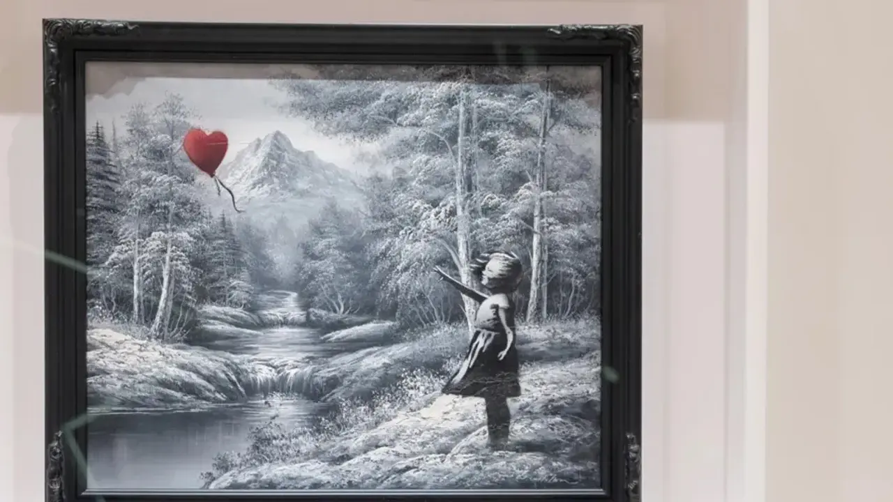 Niña con globo en forma de corazón, en un paisaje nevado con montañas y un río.