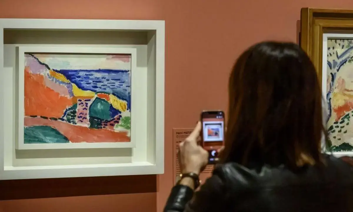 Una mujer fotografía una vibrante obra de Henri Matisse, capturando la esencia del Mediterráneo con sus audaces pinceladas y colores vivos.