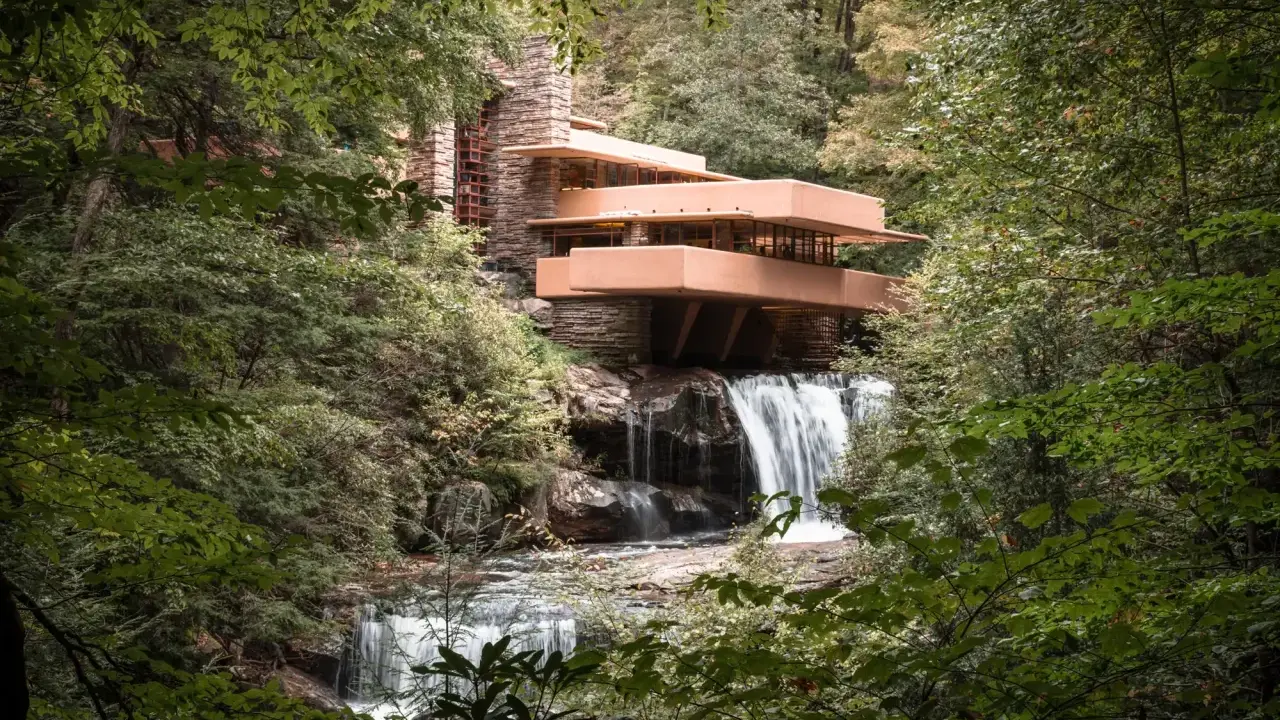 Casa de la Cascada, una obra maestra de las estructuras diseñadas por Frank Lloyd Wright, se alza sobre una cascada en un bosque frondoso.