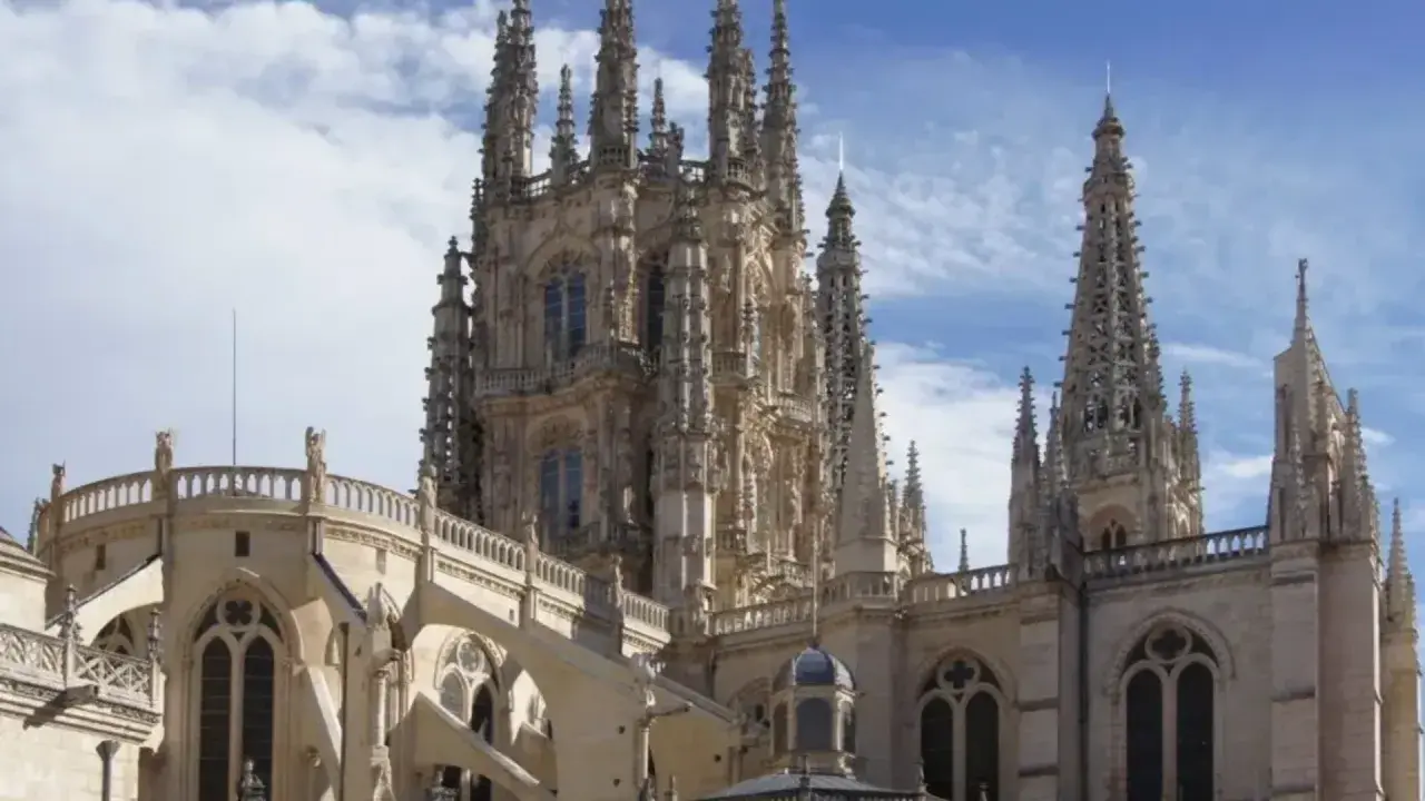 Majestuosa catedral gótica, un ejemplo de diversos **architectural styles**, con intrincadas agujas y arbotantes bajo un cielo azul.