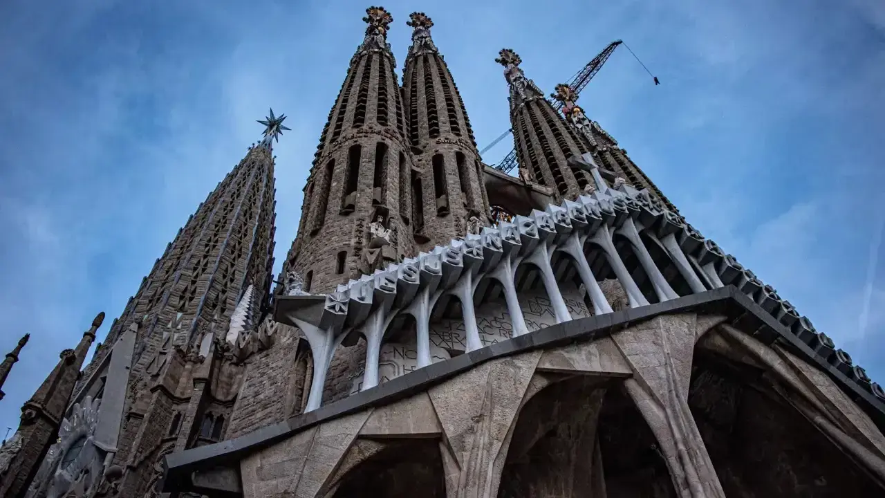 La Sagrada Familia, un espectáculo de arquitectura gótica y moderna, con grúas que sugieren su construcción continua. Un antes y después de una obra maestra.