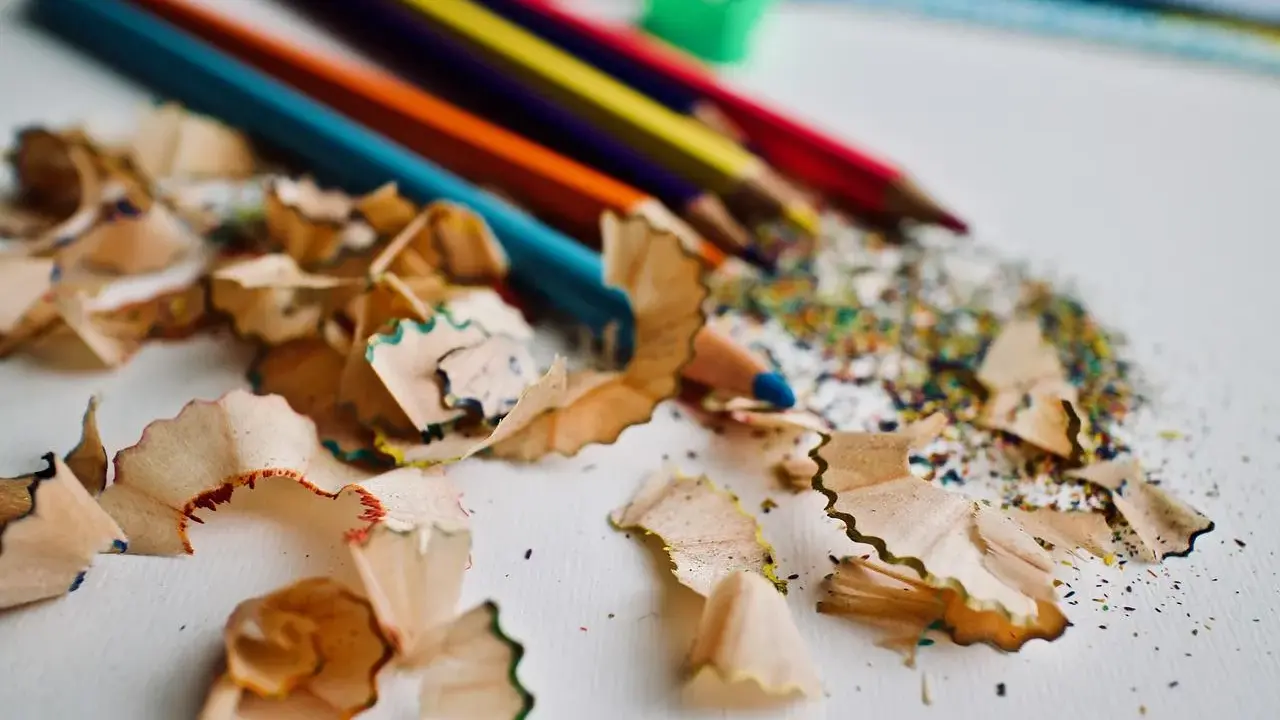 Virutas de lápices de colores y un sacapuntas verde. Un recordatorio de cómo pintar con lápices de colores y crear arte.