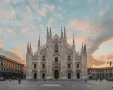 La majestuosa Catedral de Milán, una de las más impresionantes catedrales del mundo, se alza bajo un cielo crepuscular con nubes rosadas.