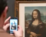 Un visitante fotografía la Mona Lisa con bigote y perilla, una de las obras de arte de Marcel Duchamp, en un museo.