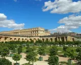 Jardines del Palacio de Versalles, un lugar lleno de curiosidades, con árboles en macetas y un cielo azul con nubes.