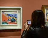 Una mujer fotografía una vibrante obra de Henri Matisse, capturando la esencia del Mediterráneo con sus audaces pinceladas y colores vivos.