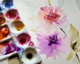 Paleta de acuarelas con pincel y flores en proceso. Inspiración para pintar con acuarelas.