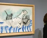 Una mujer observa una pintura de **Pablo Picasso** con una figura tumbada y un gato.