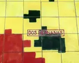 Un mosaico de azulejos amarillos, rojos y negros con el texto "DOS HERNANAS" en un recuadro.