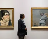 Un hombre observa dos obras de Lucian Freud: un retrato de mujer y una figura masculina con niños.