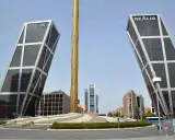 Dos icónicas estructuras diseñadas por Santiago Calatrava se alzan inclinadas, flanqueando una columna dorada.