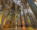 Interior de la Sagrada Familia, una de las **obras de Antoni Gaudí**, con columnas que parecen árboles y vitrales de colores que inundan el espacio.