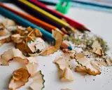 Virutas de lápices de colores y un sacapuntas verde. Un recordatorio de cómo pintar con lápices de colores y crear arte.