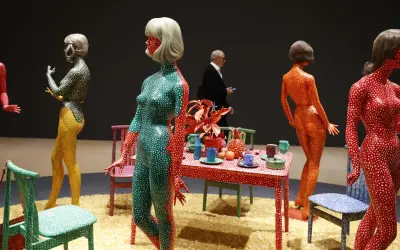 Figuras humanas cubiertas de lunares, parte de las **obras de arte de Yayoi Kusama**, junto a una mesa con objetos decorativos.