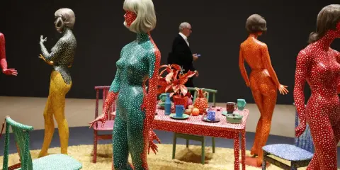 Figuras humanas cubiertas de lunares, parte de las **obras de arte de Yayoi Kusama**, junto a una mesa con objetos decorativos.