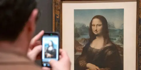 Un visitante fotografía la Mona Lisa con bigote y perilla, una de las obras de arte de Marcel Duchamp, en un museo.