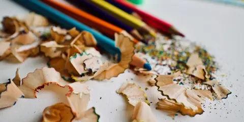 Virutas de lápices de colores y un sacapuntas verde. Un recordatorio de cómo pintar con lápices de colores y crear arte.
