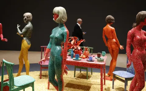 Figuras humanas cubiertas de lunares, parte de las **obras de arte de Yayoi Kusama**, junto a una mesa con objetos decorativos.