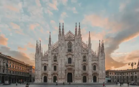 La majestuosa Catedral de Milán, una de las más impresionantes catedrales del mundo, se alza bajo un cielo crepuscular con nubes rosadas.