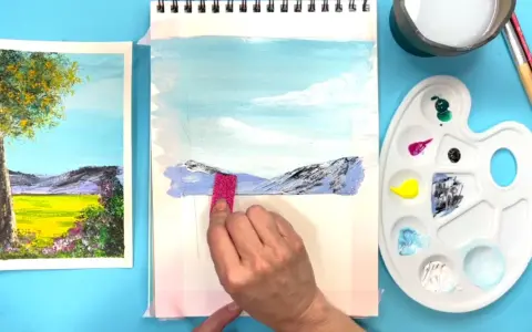 Creando dibujos de paisajes fáciles. Una mano aplica pintura a un lienzo con montañas y cielo azul.