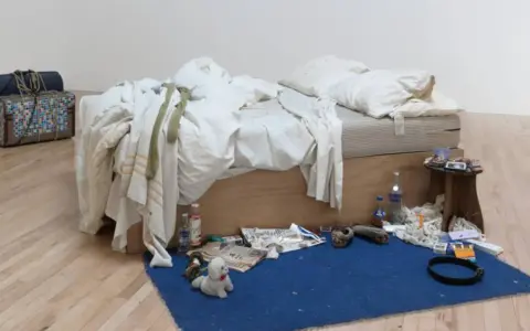 La cama deshecha de Tracey Emin, rodeada de objetos personales, botellas y maletas, evoca una historia de vida.