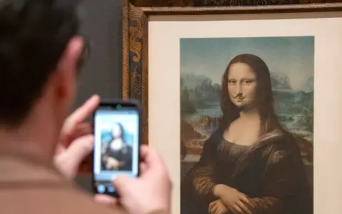 Un visitante fotografía la Mona Lisa con bigote y perilla, una de las obras de arte de Marcel Duchamp, en un museo.