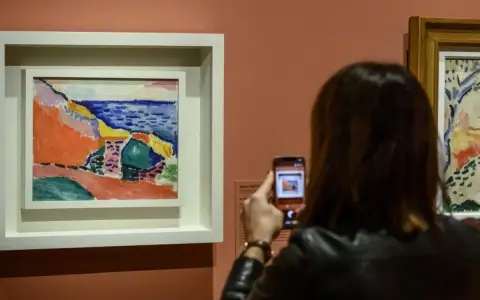 Una mujer fotografía una vibrante obra de Henri Matisse, capturando la esencia del Mediterráneo con sus audaces pinceladas y colores vivos.