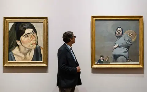 Un hombre observa dos obras de Lucian Freud: un retrato de mujer y una figura masculina con niños.
