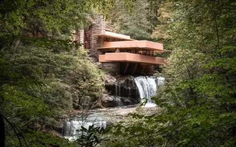 Casa de la Cascada, una obra maestra de las estructuras diseñadas por Frank Lloyd Wright, se alza sobre una cascada en un bosque frondoso.