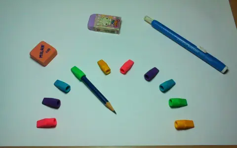 Un lápiz azul con goma de borrar de colores y dos gomas de borrar, una naranja y otra morada con un conejo, listas para un dibujo.