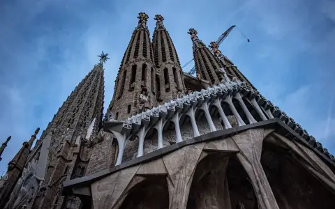 La Sagrada Familia, un espectáculo de arquitectura gótica y moderna, con grúas que sugieren su construcción continua. Un antes y después de una obra maestra.