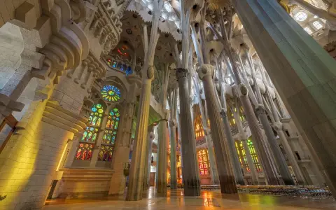 Interior de la Sagrada Familia, una de las **obras de Antoni Gaudí**, con columnas que parecen árboles y vitrales de colores que inundan el espacio.