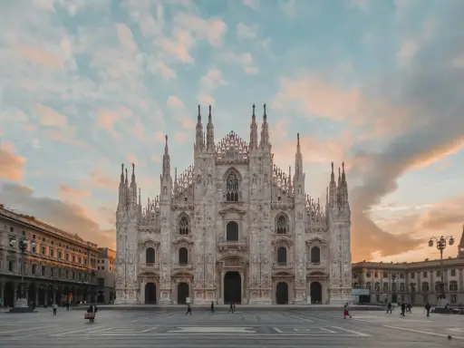 La majestuosa Catedral de Milán, una de las más impresionantes catedrales del mundo, se alza bajo un cielo crepuscular con nubes rosadas.