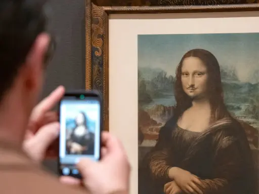 Un visitante fotografía la Mona Lisa con bigote y perilla, una de las obras de arte de Marcel Duchamp, en un museo.
