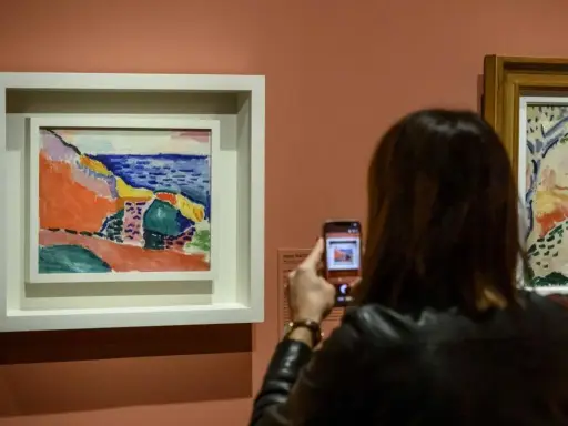 Una mujer fotografía una vibrante obra de Henri Matisse, capturando la esencia del Mediterráneo con sus audaces pinceladas y colores vivos.