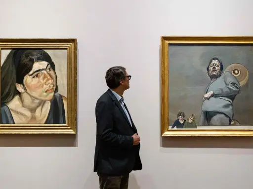 Un hombre observa dos obras de Lucian Freud: un retrato de mujer y una figura masculina con niños.