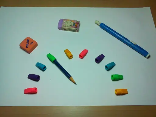 Un lápiz azul con goma de borrar de colores y dos gomas de borrar, una naranja y otra morada con un conejo, listas para un dibujo.