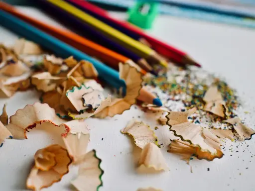Virutas de lápices de colores y un sacapuntas verde. Un recordatorio de cómo pintar con lápices de colores y crear arte.