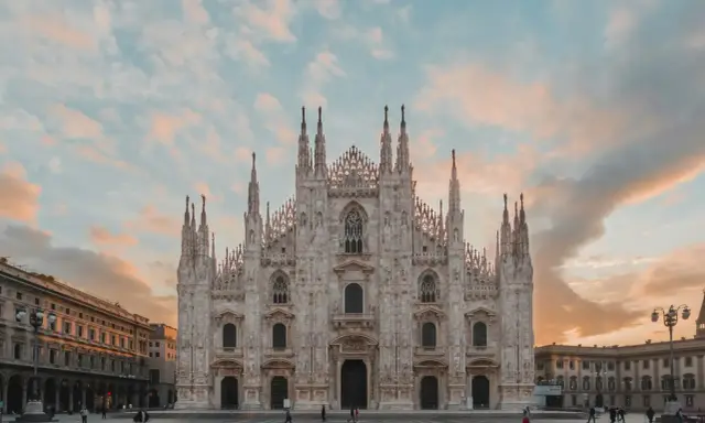 La majestuosa Catedral de Milán, una de las más impresionantes catedrales del mundo, se alza bajo un cielo crepuscular con nubes rosadas.