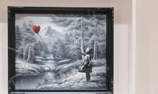 Niña con globo en forma de corazón, en un paisaje nevado con montañas y un río.