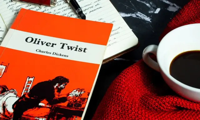 Un libro de "Oliver Twist" y una taza de café, ideal para un resumen de la historia.