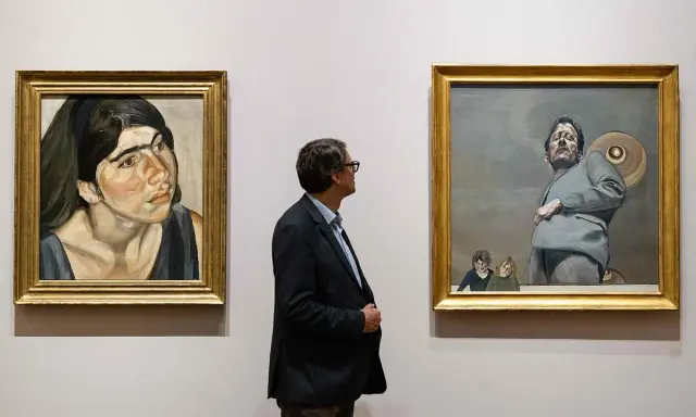 Un hombre observa dos obras de Lucian Freud: un retrato de mujer y una figura masculina con niños.