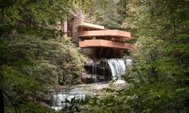 Casa de la Cascada, una obra maestra de las estructuras diseñadas por Frank Lloyd Wright, se alza sobre una cascada en un bosque frondoso.