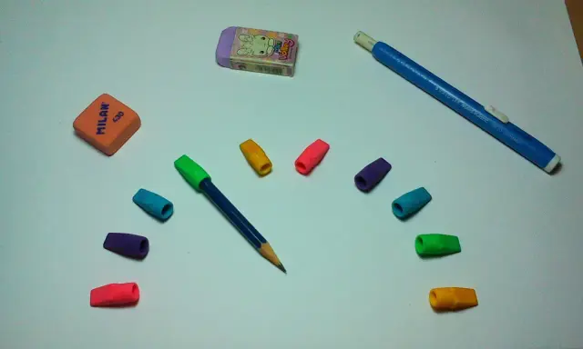 Un lápiz azul con goma de borrar de colores y dos gomas de borrar, una naranja y otra morada con un conejo, listas para un dibujo.