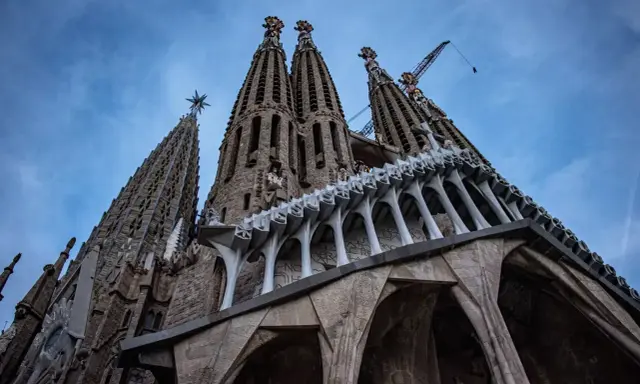 La Sagrada Familia, un espectáculo de arquitectura gótica y moderna, con grúas que sugieren su construcción continua. Un antes y después de una obra maestra.