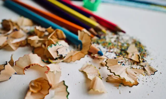 Virutas de lápices de colores y un sacapuntas verde. Un recordatorio de cómo pintar con lápices de colores y crear arte.