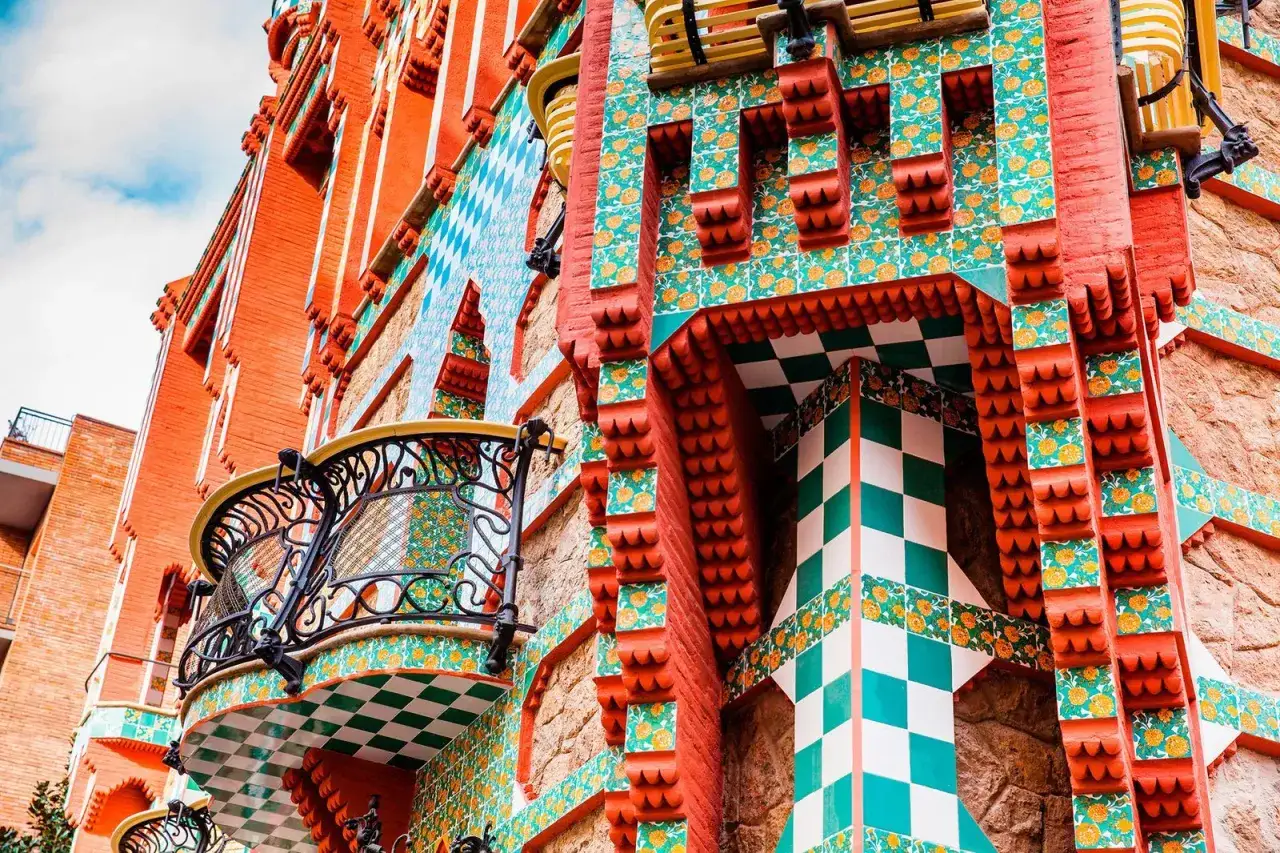 Detalle de una fachada colorida, con azulejos florales y ajedrezados, que evoca el estilo &uacute;nico de las obras de Antoni Gaud&iacute;.