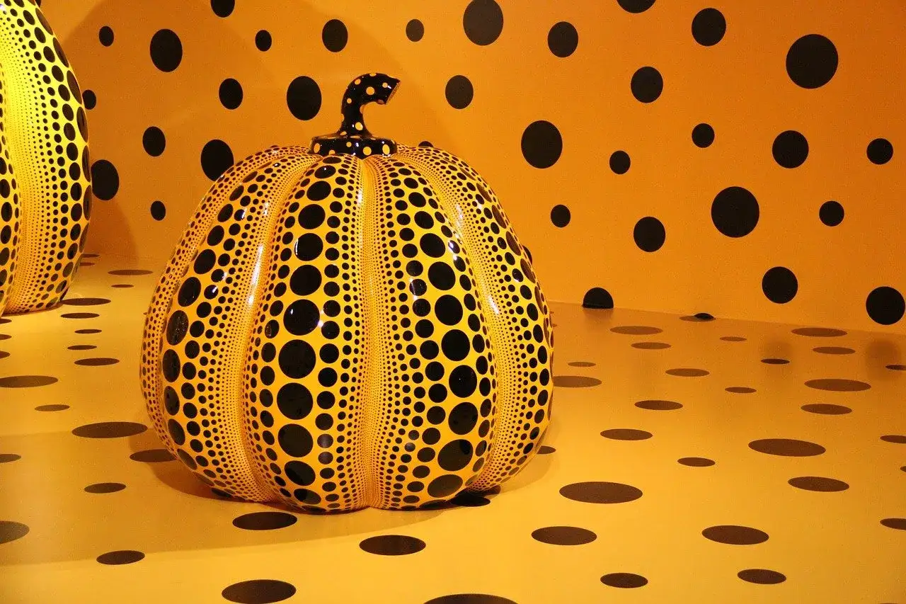 Calabaza amarilla con puntos negros, una de las ic&oacute;nicas obras de arte de Yayoi Kusama, rodeada de un patr&oacute;n similar en la pared y el suelo.