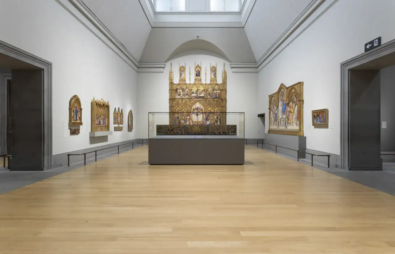 Sala de la National Gallery con impresionantes cuadros dorados y vitrinas exhibiendo arte antiguo.
