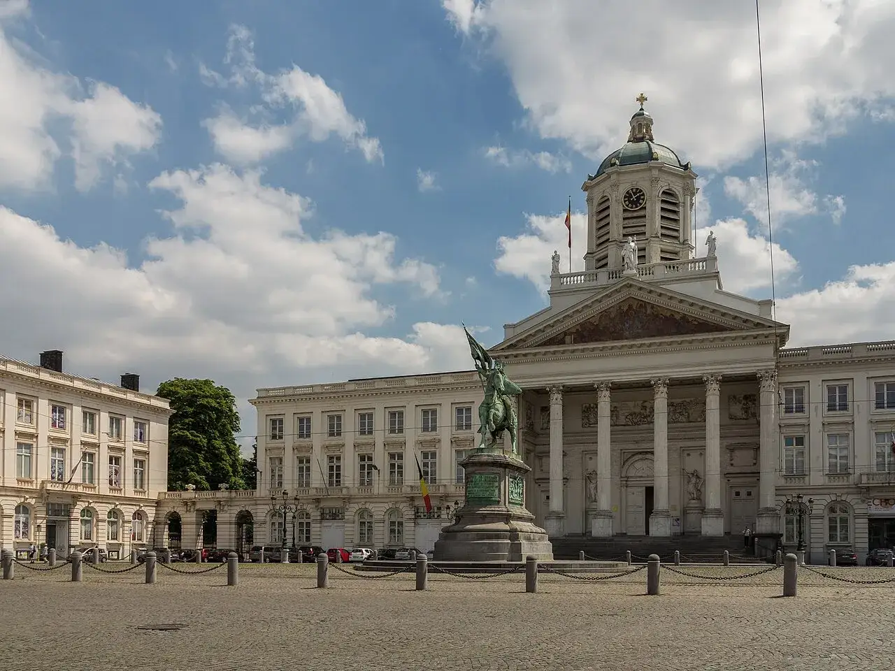 Estatua ecuestre frente a la imponente fachada de los Museos Reales de Bellas Artes de B&eacute;lgica, bajo un cielo nublado.